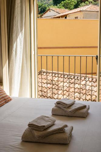 two towels are sitting on a bed in front of a window at B&B Giulia in Taormina