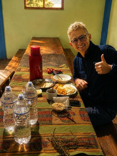 a man sitting at a table with a plate of food at Ebenezer Salkantay Huts in Colcapampa