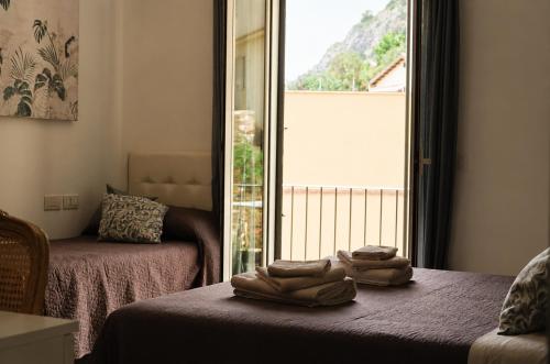 a room with two beds and a large window at B&B Giulia in Taormina