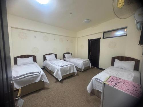 a room with three beds with white sheets at فندق ومطعم درة علي in Qaryatal Karkāshīyah
