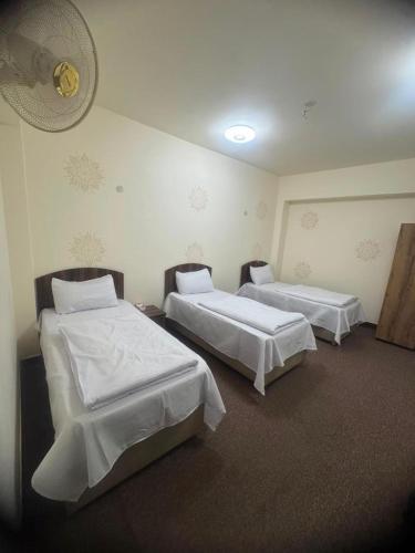 a room with two beds and a fan on the wall at فندق ومطعم درة علي in Qaryatal Karkāshīyah