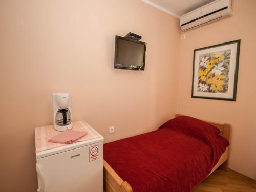 a small room with a bed and a small refrigerator at Rooms Nadica in Baška