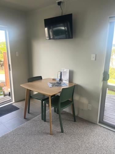 a wooden table with a chair and a tv on the wall at STAY WITH US RAGLAN - Studio in Raglan