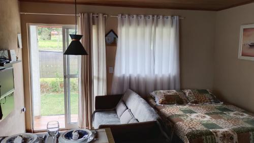 a living room with a couch and a window at Quarto- WiFi Rápido, Netflix e Cozinha Equipada in Capela do Alto