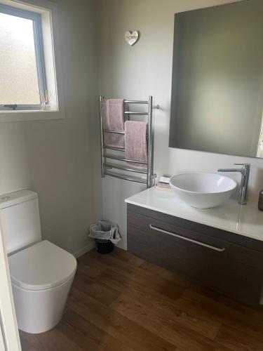 a bathroom with a white sink and a toilet at STAY WITH US RAGLAN - Studio in Raglan