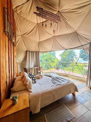 a bedroom with a large bed with a large window at Green Noise Glamping in Fraijanes