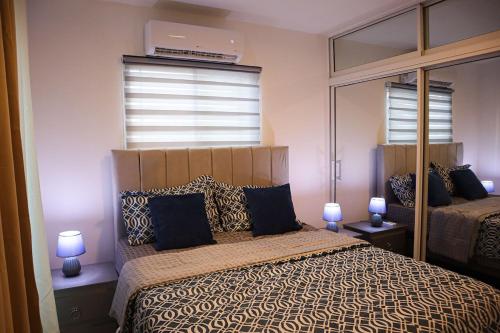a bedroom with a bed and two lamps and a window at Your Private Patio Oasis Spa Pool Lounge 2BR in Santiago de los Caballeros
