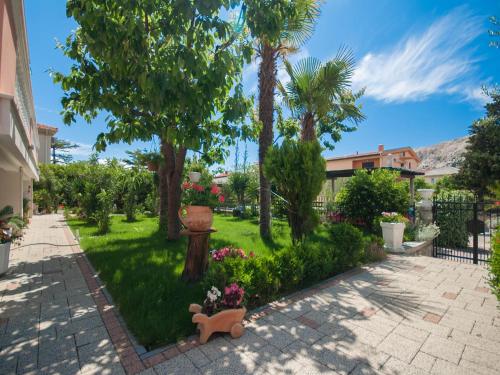 a garden with palm trees and a pathway at Rooms Nadica in Baška