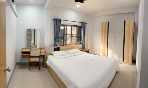 a bedroom with a white bed and a desk and a window at Tasowa House in Chiang Rai