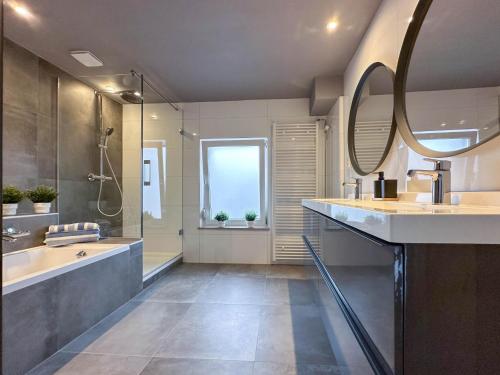 a bathroom with a tub and a sink and a mirror at Zicht op Valkenburg in Schin op Geul