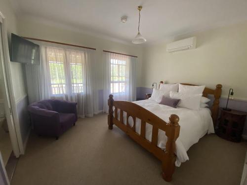 ein Schlafzimmer mit Bett, Stuhl und Fenstern in der Unterkunft Loggers Rest B&B in Stanthorpe