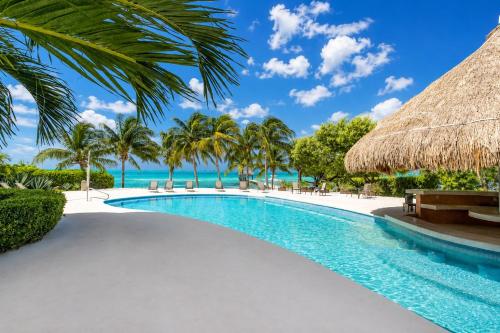 a swimming pool with palm trees and the ocean at Sunset Condo 104 Puerta al Mar Isla Mujeres Mexico in Isla Mujeres