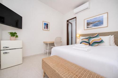 a white bedroom with a large bed and a table at Room 14: Chill City Veranda Near Miramar in San Juan