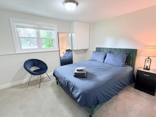 a bedroom with a bed with a blue comforter and a chair at Glam Parkville Experience! in Parkville