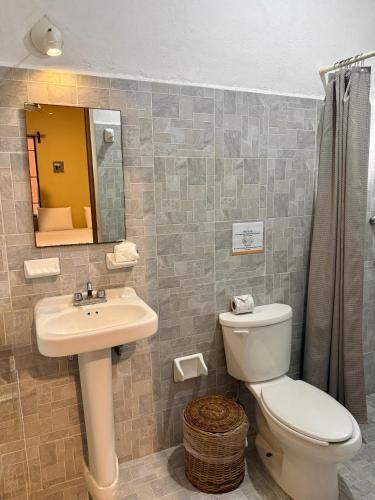 ein Badezimmer mit Toilette, Waschbecken und Spiegel in der Unterkunft Hotel Bacalar Sunshine in Bacalar