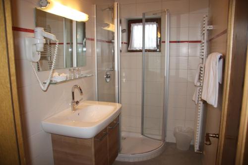La salle de bains est pourvue d'un lavabo et d'une douche. dans l'établissement Landhaus Seehof, à Füssen