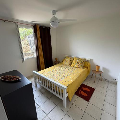a bedroom with a bed with yellow sheets and a window at Villa Floru in Le Carbet