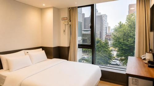 a bedroom with a white bed and a large window at Jongno The Stay Korea in Seoul