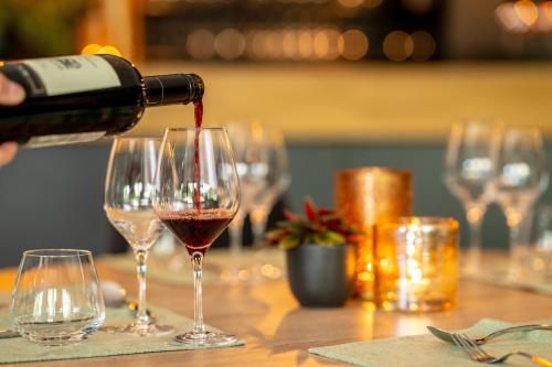 a person pouring wine into two wine glasses on a table at Landal Namur Nature in Gesves