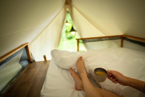 a person laying on a bed with a cup of coffee at Landal Namur Nature in Gesves