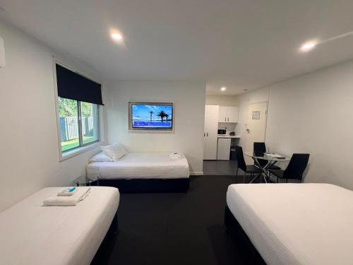 a hotel room with two beds and a table at The Esplanade Motel in Warners Bay