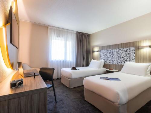 a hotel room with two beds and a desk at Ibis Styles Lyon Gorge de Loup Saphir in Lyon