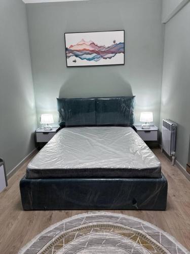 a large bed in a room with two tables at Чарвак дарвозаси люкс апартамент, дом в горах с видом in Khŭjakent