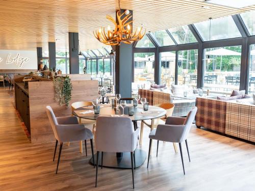 a restaurant with tables and chairs and a chandelier at Novotel Rouen Sud Zenith Parc Expo in Saint-Étienne-du-Rouvray