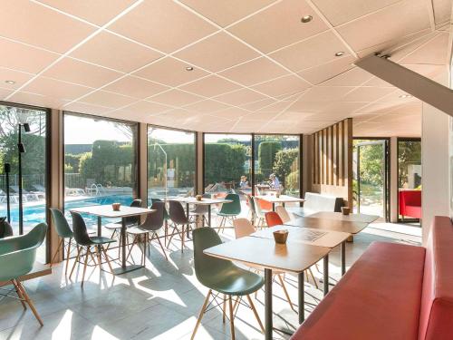 a restaurant with tables and chairs and a pool at ibis Avignon Sud in Avignon