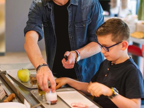 a man helping a young boy make a drink at ibis Avignon Centre Gare in Avignon