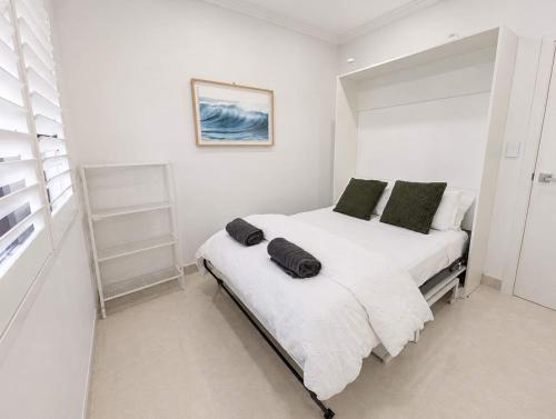 a bedroom with a bed with white sheets and green pillows at Cara Luxe Stays at Regents Park near Olympic Park and DFO in Regents Park