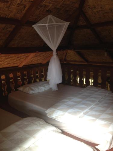 a bedroom with a bed with a mosquito net at Kupu Kupu Garden Guest House & Cafe in Bukit Lawang