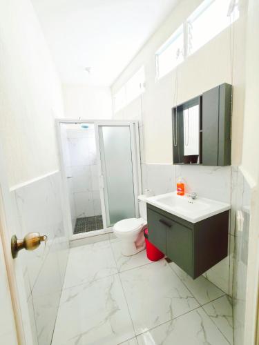 a white bathroom with a sink and a toilet at Guadalupe House Esquipulas in Esquipulas