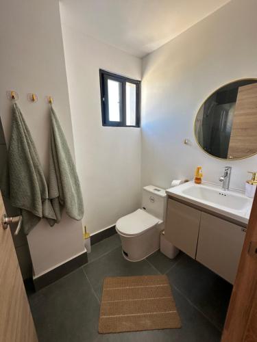 a bathroom with a toilet and a sink and a mirror at Villa Luminosa in Punta Cana