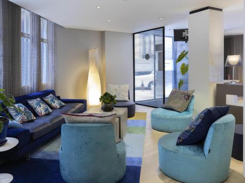 a living room with blue couches and chairs at Mercure Nice Centre Grimaldi in Nice