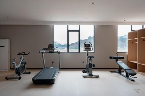 a gym with treadmills and ellipticals in a room with windows at vangvieng THAVIKUN HOTEL in Vang Vieng
