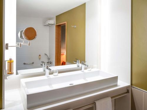 a white bathroom with two sinks and a mirror at Hotel Mercure Porto Gaia in Vila Nova de Gaia
