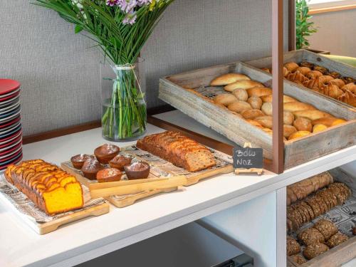a shelf with different types of pastries and bread at Hotel Mercure Porto Gaia in Vila Nova de Gaia