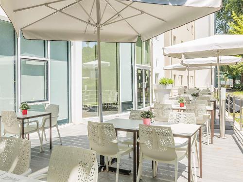 a patio with tables and chairs and umbrellas at Hotel ibis Lisboa Alfragide in Lisbon