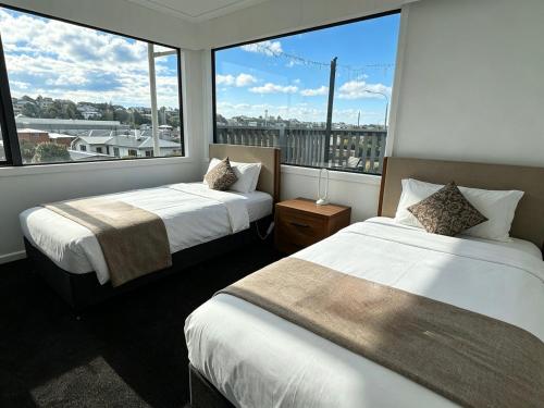 two beds in a room with a large window at Home Inn Timaru in Timaru