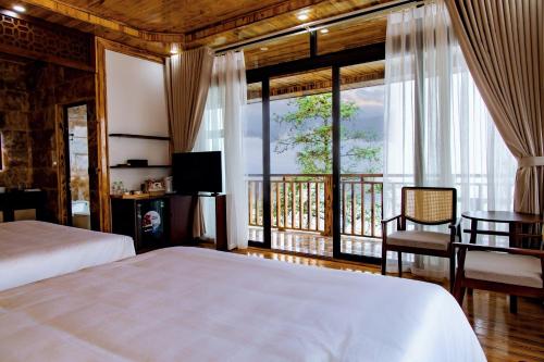 a bedroom with a large bed and a balcony at Sapa Rose Garden Resort in Sapa