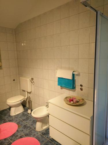 a bathroom with a toilet and a bowl of fruit on a counter at Apartman Lana in Klimno