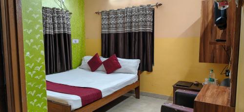 a small bed with red pillows in a room at Zeromiles Green Park in Digha