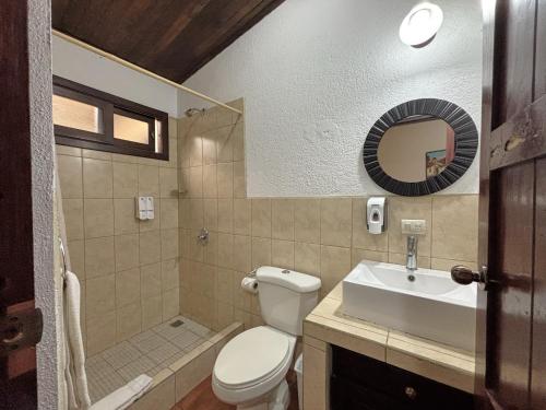 a bathroom with a toilet and a sink and a mirror at Alana Hotel By ISH in Antigua Guatemala