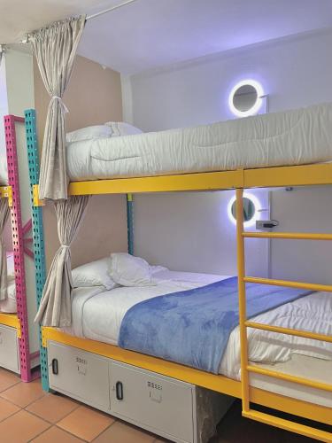 two bunk beds in a dorm room with blue sheets at Prisma Hostel in Bogotá