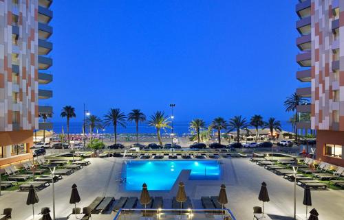 a view of a hotel pool with chairs and palm trees at Meliá Costa del Sol in Torremolinos