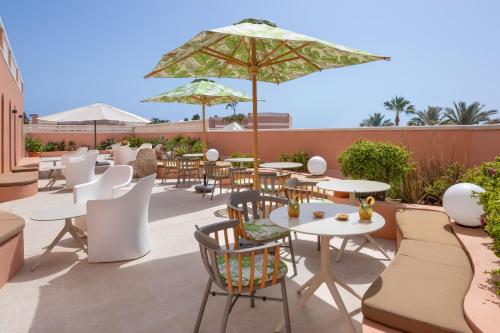 a patio with tables and chairs and an umbrella at SOL by Meliá Sun Beach Apartamentos in Adeje