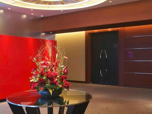 a room with a glass table with a vase of flowers at Mercure Sapporo in Sapporo
