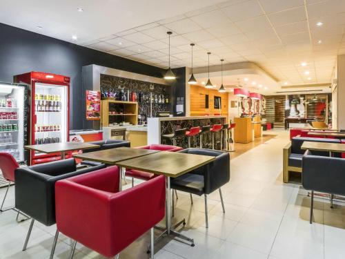 a restaurant with tables and chairs and a bar at ibis Barretos in Barretos