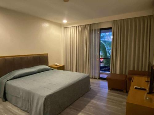 a bedroom with a bed and a large window at Bayfront Hotel Subic in Olongapo